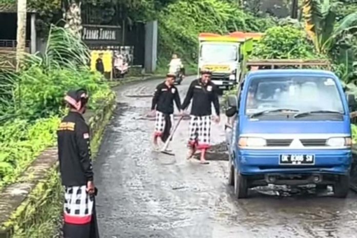 Rusak, Pecalang Tambal Jalan Berlubang Di Jembatan Padangtunggal 1